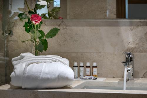 a bathroom sink with a towel and a rose at Civitel Akali Hotel in Chania