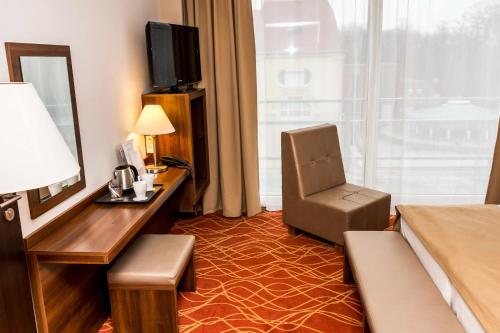 a hotel room with a bed and a desk with a chair at Bonvital Hotel Hévíz Superior Adults Only in Hévíz