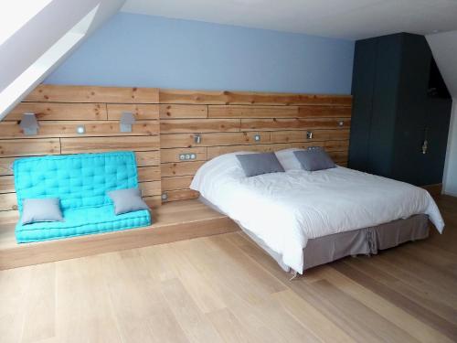 a bedroom with a bed and a blue chair at La Couture du Charme in Saméon