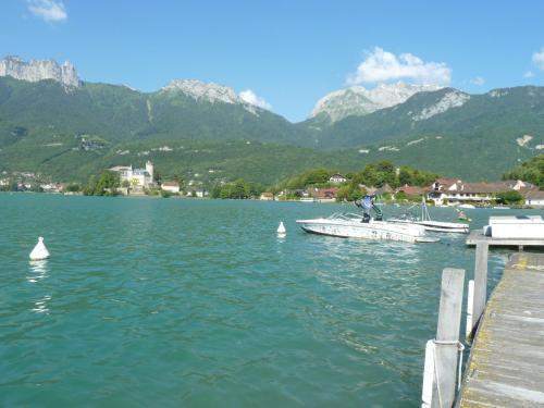 a boat on a lake with mountains in the background at la baie des voiles ,vue lac d'Annecy ,plage privée in Duingt