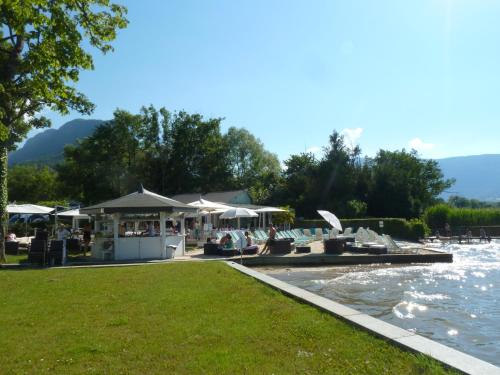 a pool with chairs and umbrellas next to the water at la baie des voiles ,vue lac d'Annecy ,plage privée in Duingt