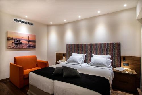 a bedroom with a bed and an orange chair at Civitel Akali Hotel in Chania Town