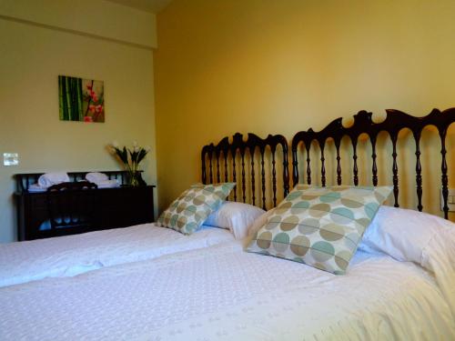 a bedroom with a bed with white sheets and pillows at Los Acebos in Otero de Herreros