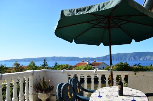 a table with a green umbrella on a balcony at Apartments Stivic in Pinezici