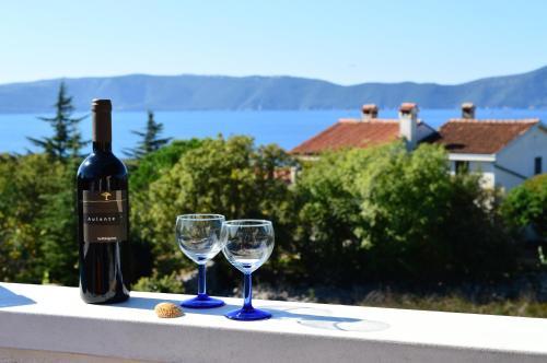 a bottle of wine and two wine glasses on a ledge at Apartments Stivic in Pinezici