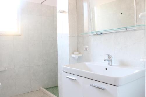 a white bathroom with a sink and a mirror at Hotel Garden in Vlorë