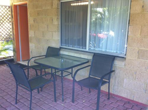 a glass table and chairs on a patio at Mango Tree Motel in Agnes Water