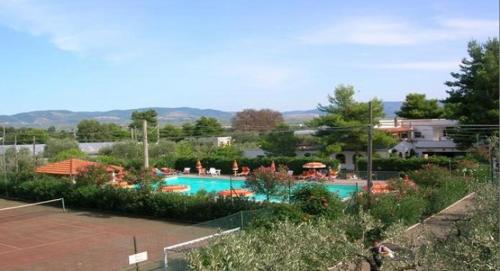 a swimming pool with a tennis court and a house at VIOLA Club Village & Camping in Foce Varano