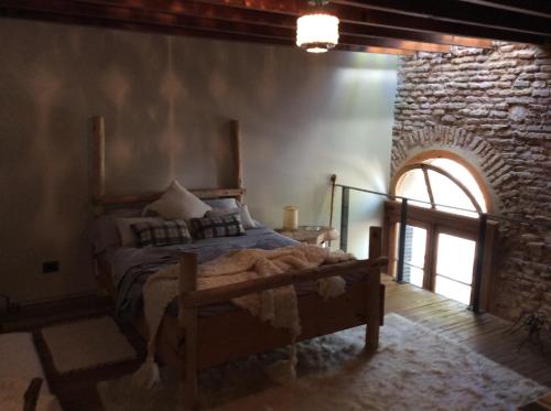 a bedroom with a bed in a room with a stone wall at Las Glicinas Boutique Apartments in Colonia del Sacramento