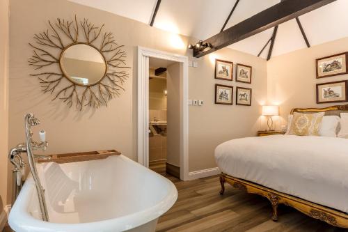 a bathroom with a tub and a bed and a mirror at Cowdray Lodge B&B rooms in Midhurst