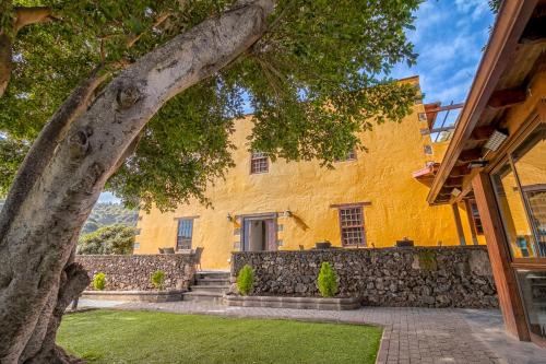 un edificio amarillo con un árbol delante de él en Hotel Rural LIVVO Maipez, en Las Palmas de Gran Canaria