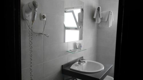 La salle de bains blanche est pourvue d'un lavabo et d'une fenêtre. dans l'établissement Kristal, à Torremolinos