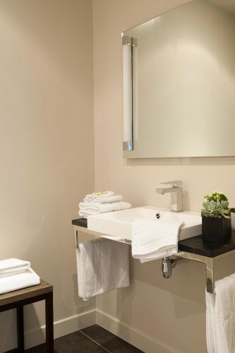 a bathroom with a sink and a mirror and towels at Hotel et restaurant Le Clos De La Prairie in Gouy-Saint-André