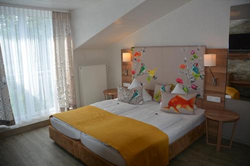 ein Schlafzimmer mit einem großen Bett und einer gelben Decke in der Unterkunft Alpina Hotel in Rosenheim