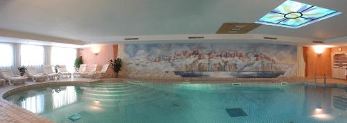 a swimming pool in a hotel with a painting on the wall at Hotel Grifone in Arabba
