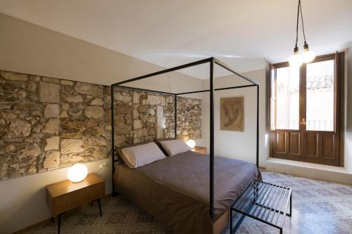 een slaapkamer met een hemelbed en een stenen muur bij Il Fuoco di Archimede - Ortigia in Siracusa