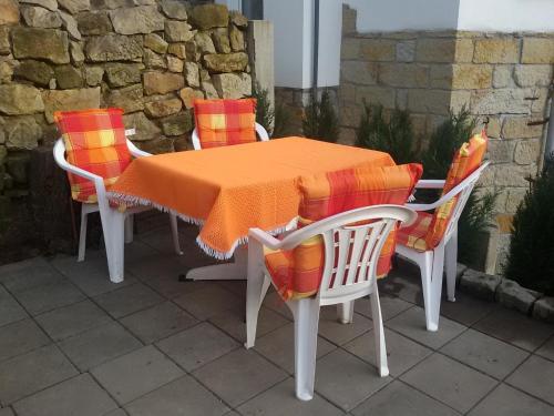 einen Tisch und vier Stühle mit orangefarbenen Decken darauf in der Unterkunft Ferienwohnung Mey in Rathmannsdorf