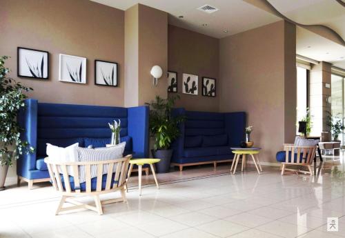 a waiting room with blue chairs and tables at Hotel Avra by Smile hotels - Free Airport Shuttle in Rafina
