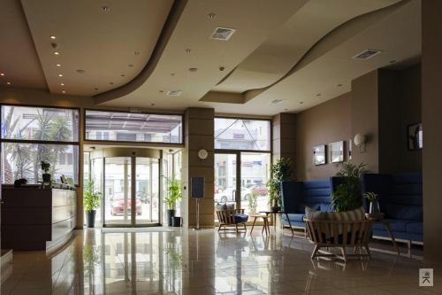 a lobby with chairs and tables in a building at Avra Hotel in Rafina