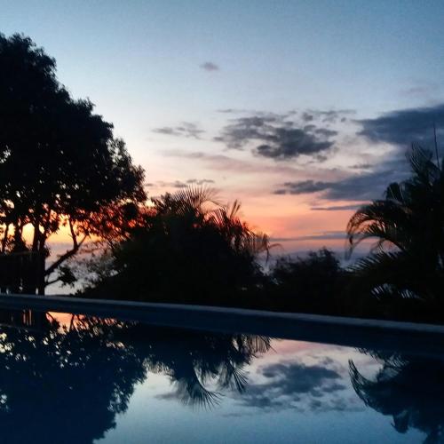 a sunset reflecting in the water of a swimming pool at Punta Duarte Garden Inn in Los Duarte