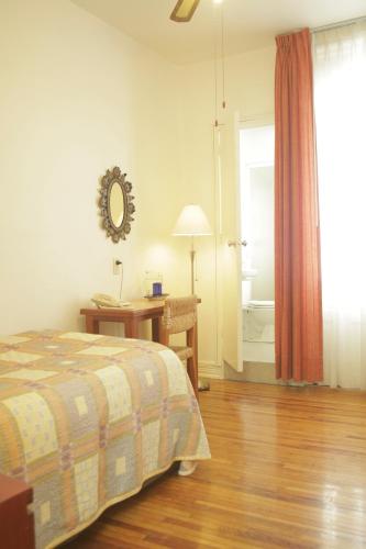 a bedroom with a bed and a desk and a window at Hotel Casa Gonzalez in Mexico City