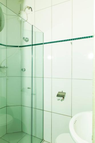 a bathroom with a glass shower and a sink at Hotel Oasis in Contagem