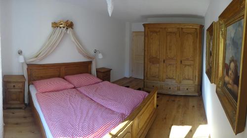 Schlafzimmer mit einem Holzbett mit rosa Bettwäsche in der Unterkunft AlpenAppartements Brand in Brand