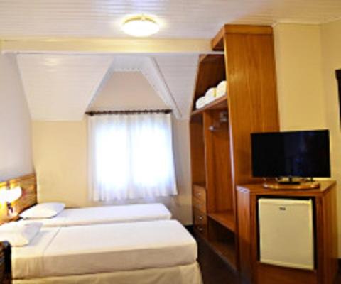 a hotel room with two beds and a television at Hotel Amoreiras in Extrema