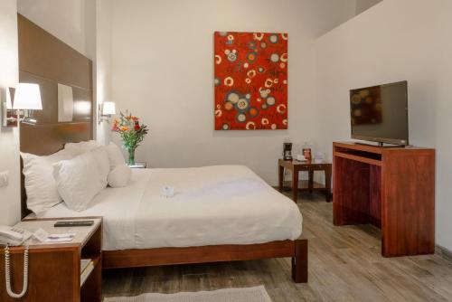 a hotel room with a bed and a flat screen tv at Hotel La Morada in San Miguel de Allende