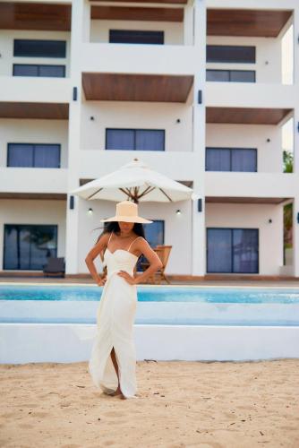 a woman in a white dress standing on the beach with an umbrella at The Ellysian Boutique Hotel in Placencia Village