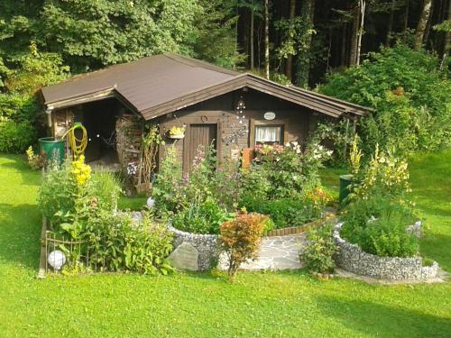 a small cabin with a bunch of flowers in the yard at Ferienwohnung Waldhäusl in Sankt Martin bei Lofer