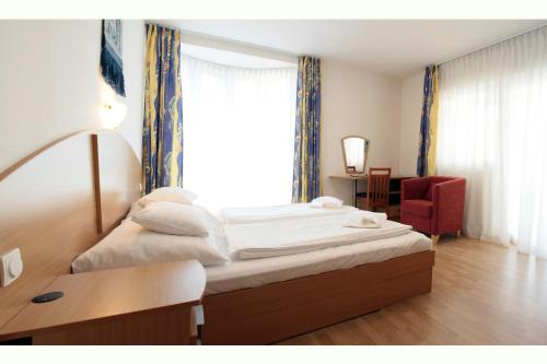 シオーフォクにあるAmore Apartmanのベッドと赤い椅子が備わるホテルルームです。