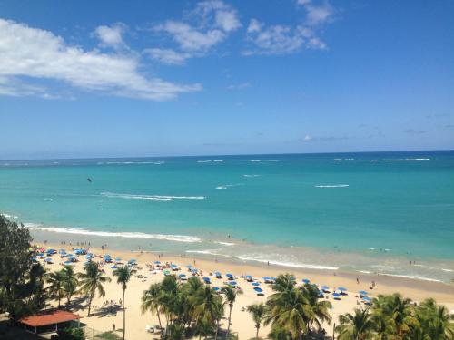 a beach with people and umbrellas and the ocean at Cozy Beachfront Studio in San Juan