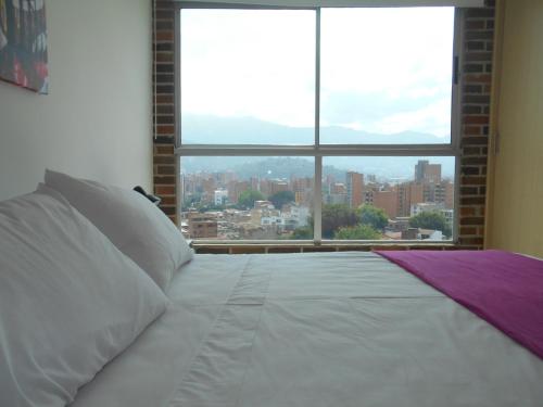 Cama en habitación con ventana grande en San Peter Suites, en Medellín