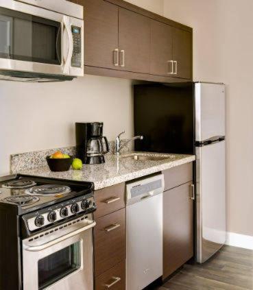 a kitchen with a stove and a refrigerator at TownePlace Suites by MarriottDetroit Canton in Canton