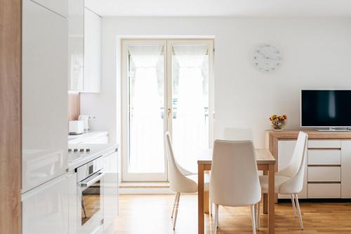 a white kitchen with a table and white chairs at Apartament 3 - Bliżej Zdroju in Polanica-Zdrój
