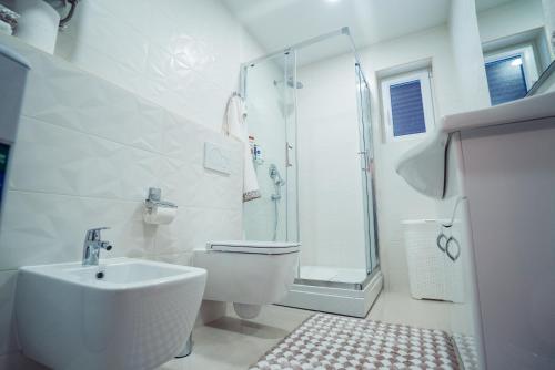 a white bathroom with a sink and a shower at Ivica Apartments in Imotski