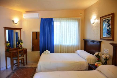 ein Hotelzimmer mit 2 Betten und einem Fenster in der Unterkunft Hotel La Hacienda in Tuxtla Gutiérrez