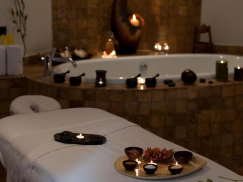 a room with a bath tub with candles and a table with a bed at Guaycura Boutique Hotel, Beach Club & Spa in Todos Santos