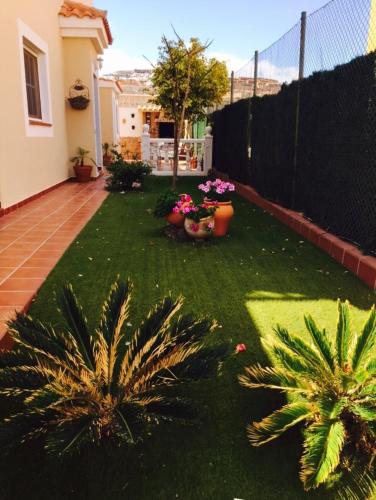 a yard with a fence and some plants and flowers at Casa Paraiso in Caleta De Fuste