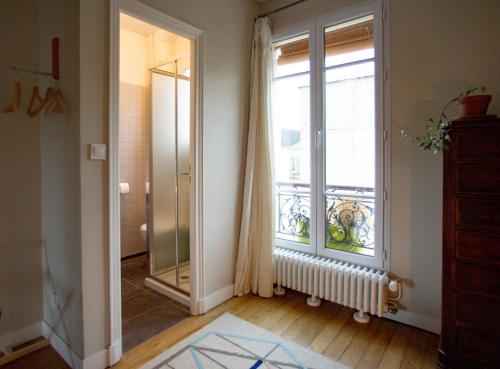 パリにあるChambre d'hôte parisienneの大きな窓と鏡が備わる客室です。