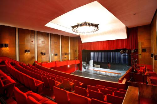 an empty auditorium with red chairs and a stage at L'Échappée - Hôtel Casino Dieppe in Dieppe