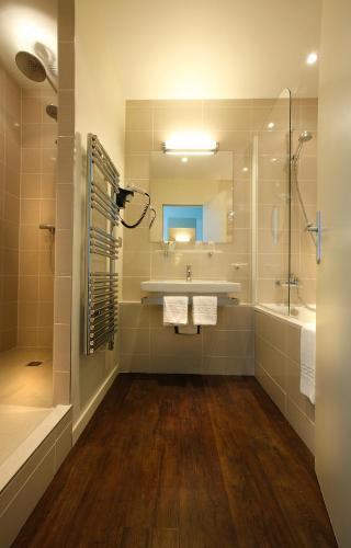 a bathroom with a tub and a sink and a mirror at L'Échappée - Hôtel Casino Dieppe in Dieppe