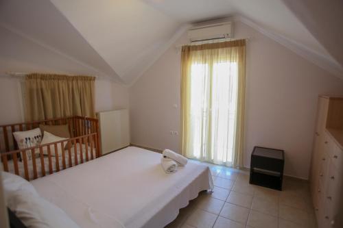 sypialnia z 2 łóżkami i łóżeczkiem dziecięcym oraz oknem w obiekcie Attic Retreat w mieście Argostoli