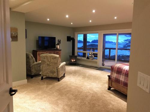 a bedroom with a bed and chairs and a television at Melfort Bell Guest Suites in Ucluelet
