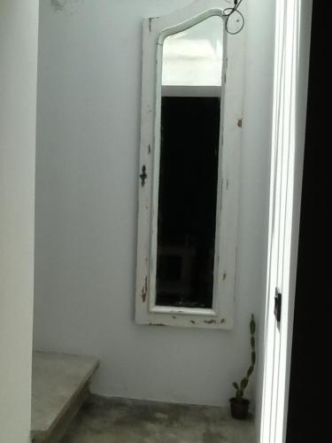 a mirror on a white wall with a window at Las Glicinas Boutique Apartments in Colonia del Sacramento