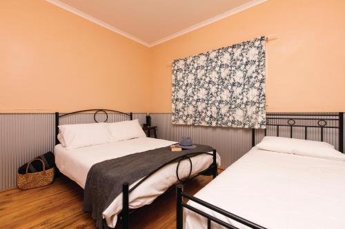 a bedroom with two beds and a window with a curtain at Mungo Shearers' Quarters in Mungo