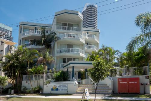 a tall white building with palm trees in front of it at Santa Anne By The Sea in Gold Coast