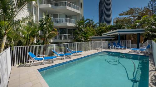 a swimming pool with chairs and a building at Santa Anne By The Sea in Gold Coast