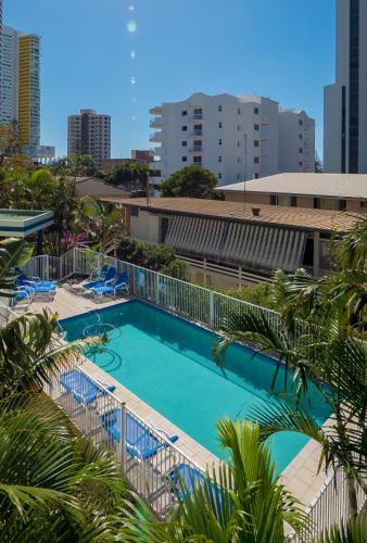 a large swimming pool with palm trees and buildings at Santa Anne By The Sea in Gold Coast